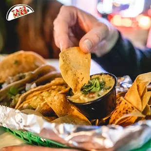 a person dipping a tortilla into a bowl
