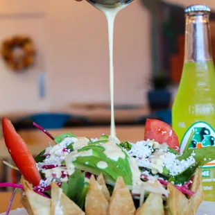 a person pouring sauce over a salad