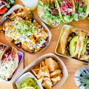 a table full of tacos, salads, and drinks