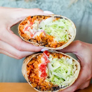 a woman holding two burritos