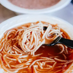 a hand holding a spoon full of pasta