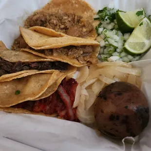Chicharron tacos, one barbacoa taco, trompo taco, side of cilantro and onions, grilled onions, and a small cooked potato.