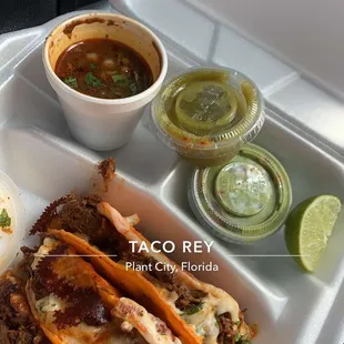 a tray of tacos with a side of sauces