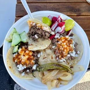 Two Carne Asada tacos. One 1/2 eaten and a brisket taco!