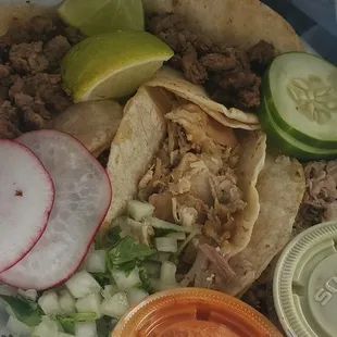 a plate of tacos, pickles, cucumbers, and pickles