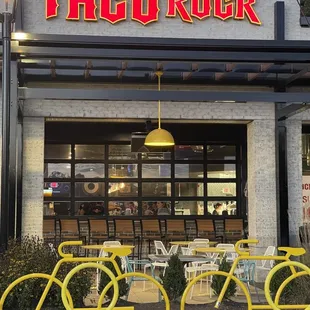 two yellow bicycles parked in front of a taco rock restaurant