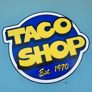 a taco shop sign on a blue wall