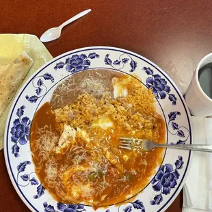 Juevos Rancheros.. eggs on top of a corn tortilla with Rice and Beans, flour Tortillas, with delicious sauce over the plate, and