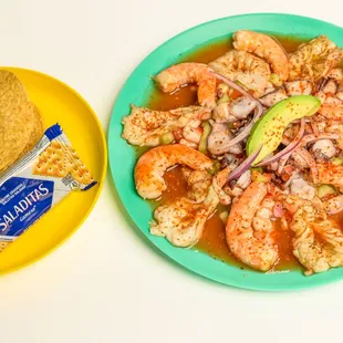a plate of shrimp, tortilla and a bag of chips