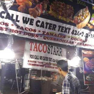 a man standing in front of a taco stand