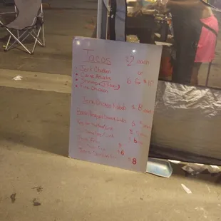 a sign in front of a taco stand