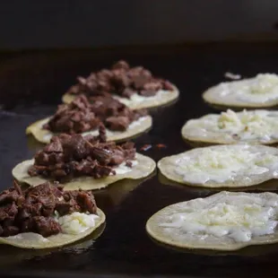 a line of tacos with meat and cheese