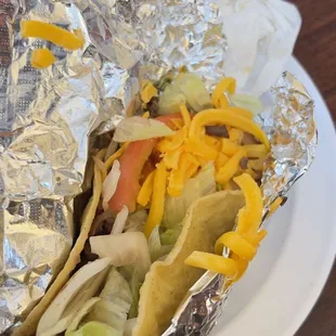 a hand holding a taco wrapped in foil