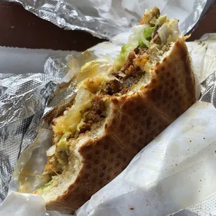 a half eaten sandwich on a piece of tin foil
