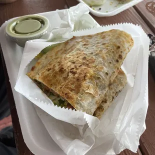 a quesadilla on a plate with a side of pickles