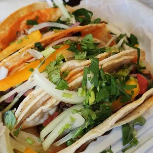 a variety of tacos in a styrofoam container