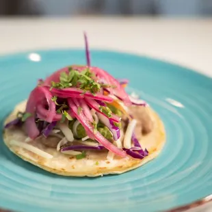 El Vegano - refried beans, guac, vegan cheese, slaw, cilantro, pickled red onions on a corn tortilla