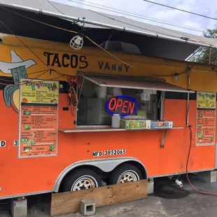 an orange food truck with menus