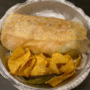 Carne asada burrito with grilled onions and peppers, chips
