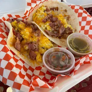 two tacos on a red and white checkered tray