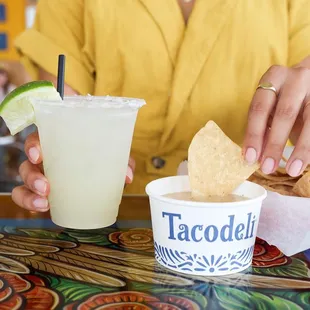 a woman holding a drink and chips