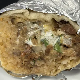 it is the beef Suadero with everything on it which is Rice, beans, guacamole, sour cream, queso, onions, cilantro, and shredded cheese.