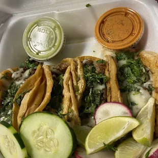 a variety of tacos in a styrofoam container