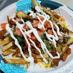 a plate of taco fries with sour cream sauce