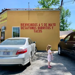 a little girl standing in front of a building