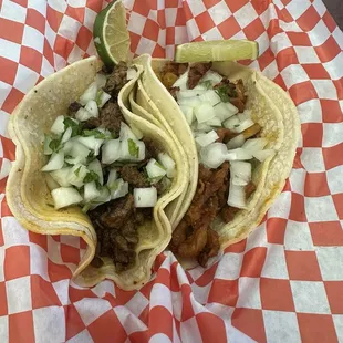 Asada and al pastor tacos with onion and cilantro on corn tortillas