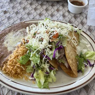 Carnitas hard shell tacos with lettuce, tomato, cheese and salsa with Mexican rice and refried beans.