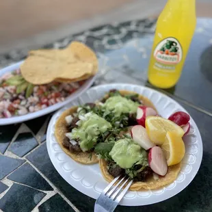 two plates of tacos and a bottle of orange juice