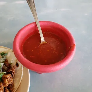 a bowl of chili sauce and a taco