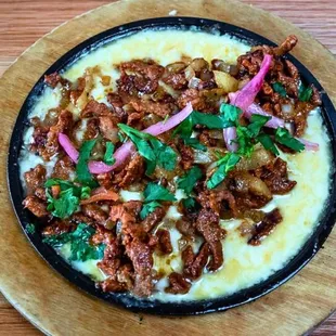 Queso Fundido Al Pastor: Melty queso chihuahua with slow-roasted pork, pineapple, onions, and cilantro. Served with warm tortillas!