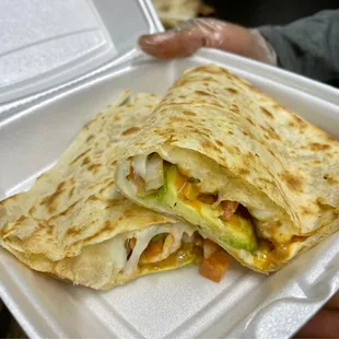 a hand holding a container of quesadilla