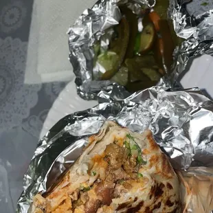 a tortilla wrapped in foil with pickles