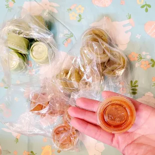 a person's hand holding a plastic container filled with donuts