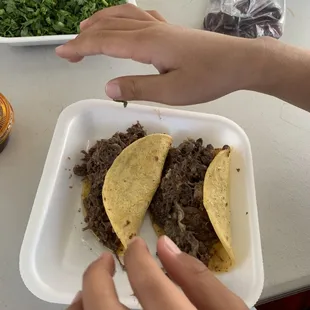 two hands reaching for a taco