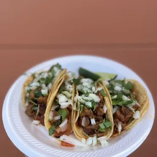 a hand holding a plate of tacos