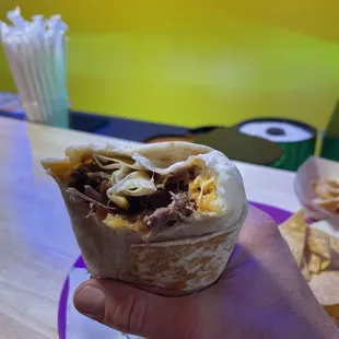a hand holding a burrito