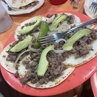 a plate of tacos with meat and avocado