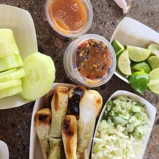 Sides: green Onions, onions and cilantro and cabbage, limes, cucumbers, salsas