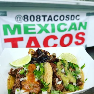 a hand holding a plate of tacos
