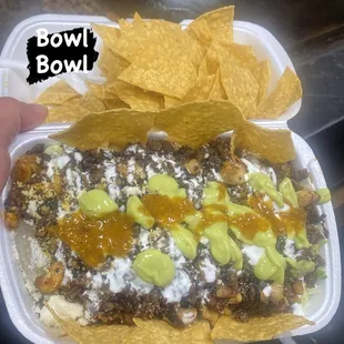 a hand holding a bowl of mexican food