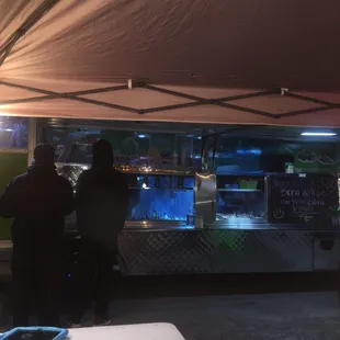 a couple of people standing in front of a food truck