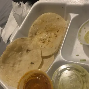 a tray of tacos and condiments