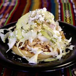 a black plate with shredded cabbage and meat