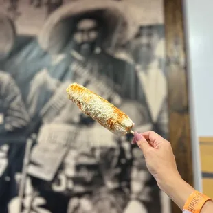 a hand holding a piece of corn