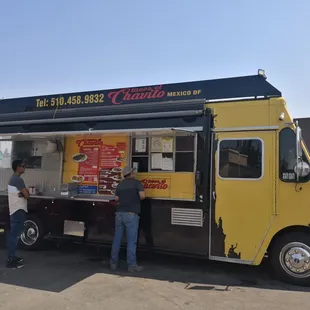 two men standing in front of a taco truck