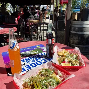 a red table with a bottle of soda and two baskets of food
